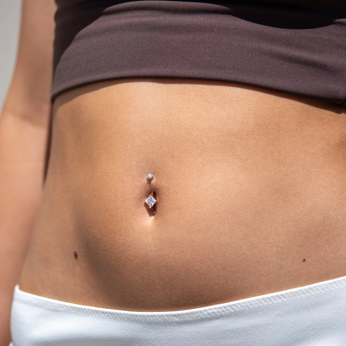 The Princess 1.5 ct Moissanite belly ring up close, paired with a brown bandeau and white skirt